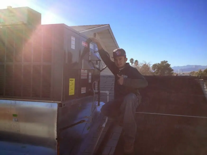 HVAC technician performing Air Duct Cleaning on a rooftop unit in Beaverton